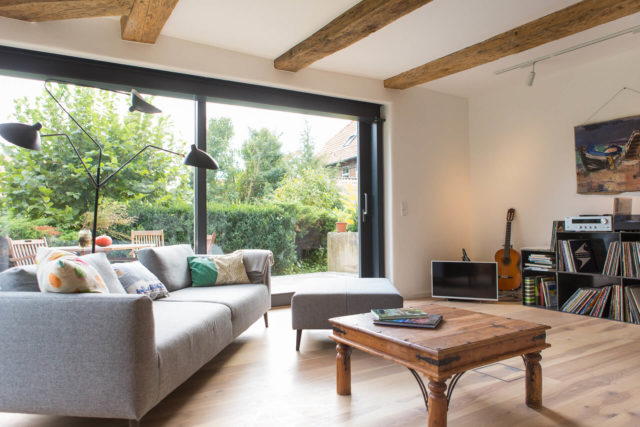 Foto Ryan Baugestaltung Fachwerkhaus Goettingen Wohnzimmer mit Couch und großen Terassenfenstern