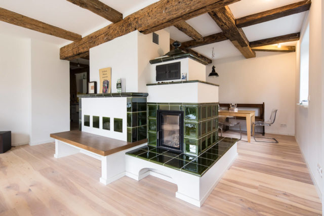 Foto Ryan Baugestaltung Fachwerkhaus Goettingen Wohnzimmer mit modernem Parkettboden und antikem Kachelofen in der Mitte